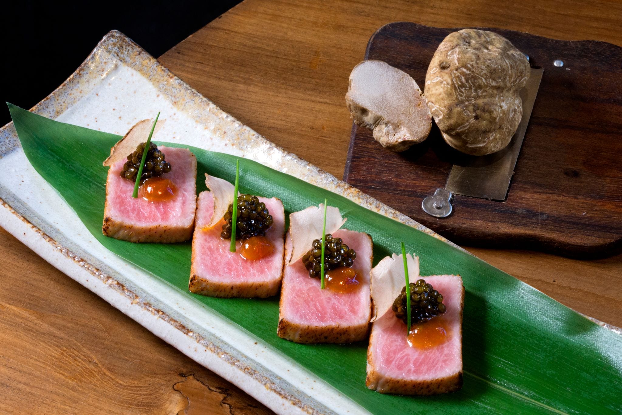 four pieces of seared fish with caviar on top